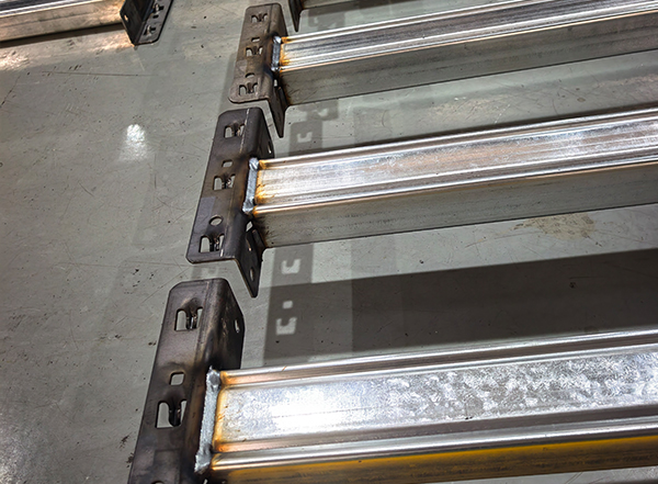 Close-up detail of welded end connectors on galvanized box beams showing precise and strong weld seams